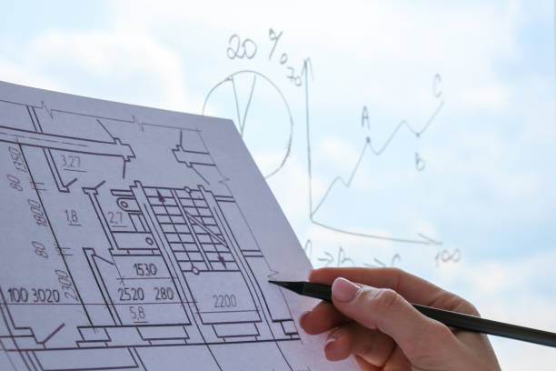 istock Female interior designer drawing house plan in office. Workplace Workspace window. Architect at work. Architectural construction plans with blueprints 1320269903