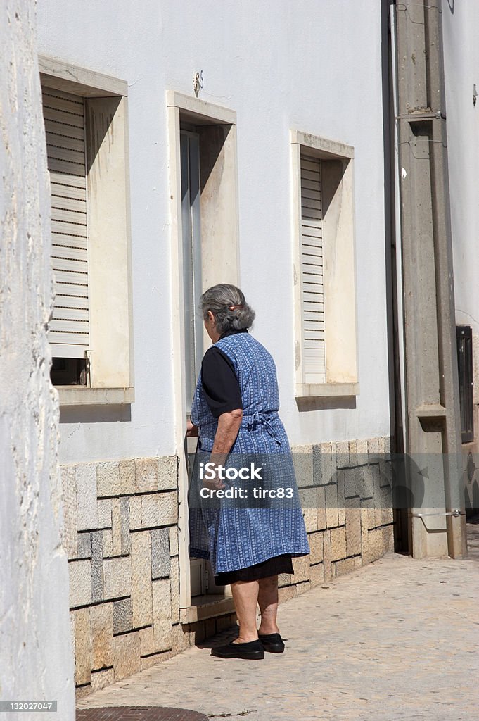 Old portugese woman entering house Adult Stock Photo