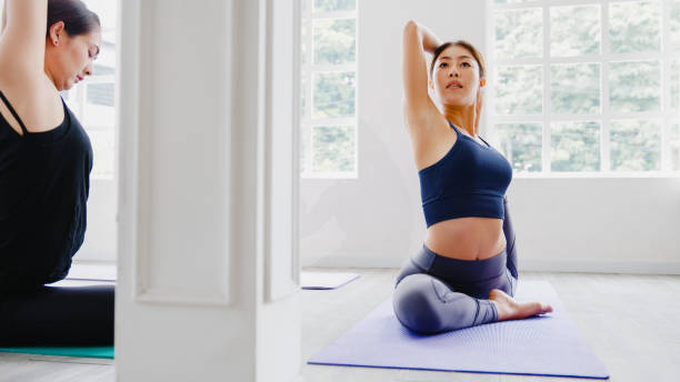 istock Young Asian sporty attractive people practicing yoga lesson with instructor. Asia group of women exercising healthy lifestyle in fitness studio. 1320273527