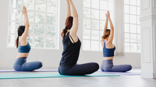istock Young Asian sporty attractive people practicing yoga lesson with instructor. Asia group of women exercising healthy lifestyle in fitness studio. 1320273549