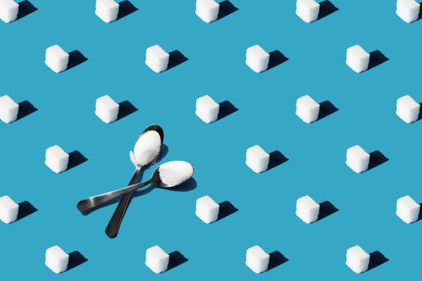 Refined sugar and spoons with white sugar pattern on a blue background. Concept of healthy eating and diabetes prevention