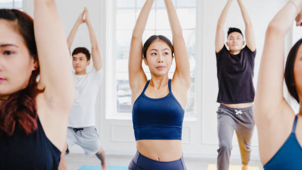 istock Young Asian sporty attractive people practicing yoga lesson with instructor. Asia group of women exercising healthy lifestyle in fitness studio. 1320274607