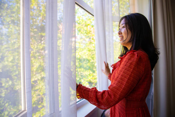 istock Woman opening window curtains enjoying good morning 1320274941