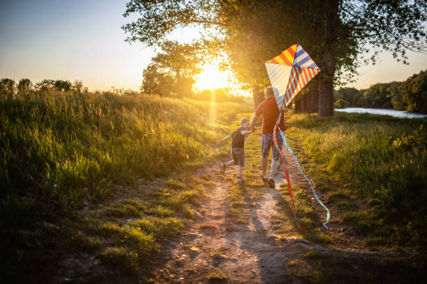 祖父と少年は自然の中で凧と一緒に走る - 凧 ストックフォトと画像