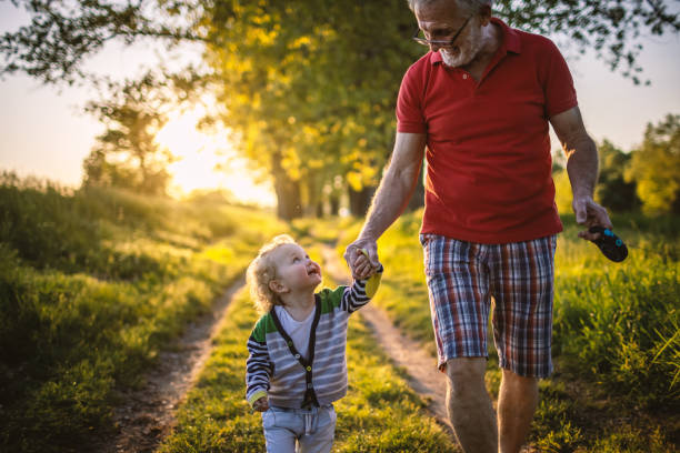 Grandfather and grandson holding hands in nature Grandfather and grandson holding hands, walking in nature. old man baby stock pictures, royalty-free photos & images