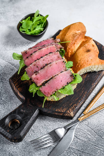 panino con bistecca di tonno in una baguette con rucola. sfondo bianco. visualizzazione dall'alto - tuna steak fillet food plate foto e immagini stock