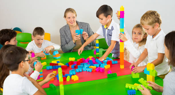 istock Teacher and happy schoolkids playing building blocks 1320280370