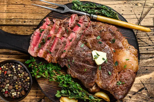 Roast rib eye beef meat steak on a cutting board. wooden background. Top view.