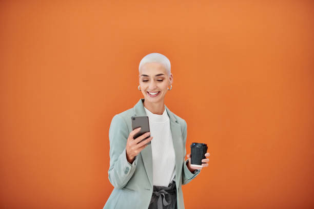 Shot of a young businesswoman using a cellphone against an orange background stock photo