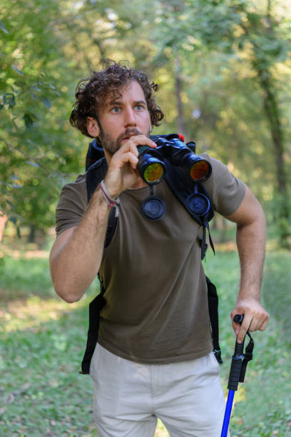 istock Young Man is Hiking in Forest in Nature and Using Binoculars. 1320285407