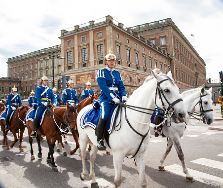 Mounted guard parade passing the Royal castle in Stockholm, Sweden. With and browned horses and blue uniforms with golden gasgets