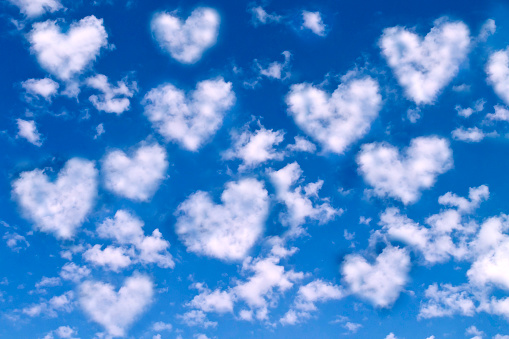 White heart shaped clouds on bright blue sky