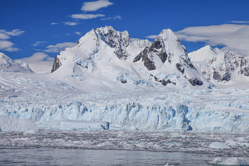 View of glacier and snowcapped mountains against cloudy sky in Cierva Cove, Trinity Peninsula, Antarctica.