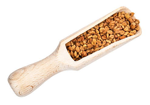 top view of Fenugreek seeds in wood scoop cutout on white background