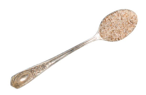 top view of Psyllium husk in silver teaspoon cutout on white background