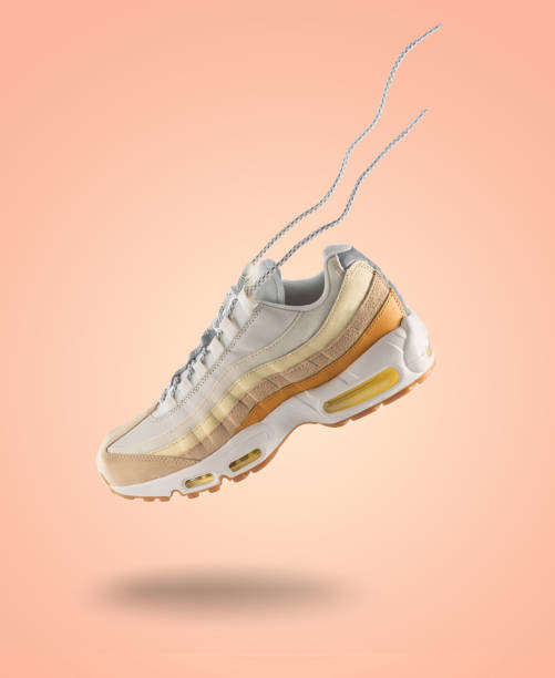 Woman sneaker on a light peach gradient background, woman's fashion, sport shoe, sneakers concept, lifestyle Woman sneaker on a light peach gradient background, woman's fashion, sport shoe, sneakers concept, lifestyle, colours yellow orange, brown nike air photos stock pictures, royalty-free photos & images