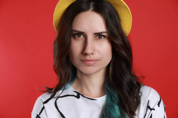 Beautiful young woman with nose piercing on red background