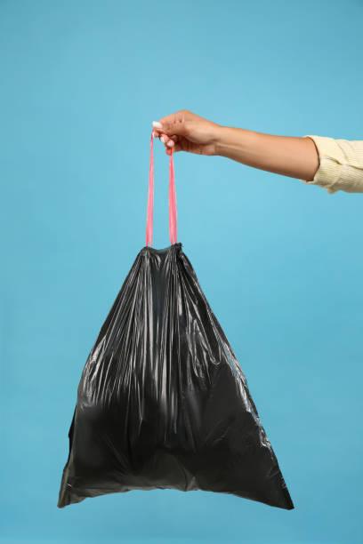 istock Woman holding full garbage bag on light blue background, closeup 1320296493
