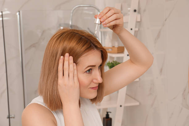 Woman applying oil onto hair at home. Baldness problem Woman applying oil onto hair at home. Baldness problem woman hairline stock pictures, royalty-free photos & images