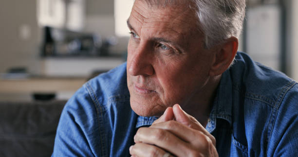 Shot of a mature man sitting alone on the sofa at home and looking contemplative I wish I could change the past man regret stock pictures, royalty-free photos & images