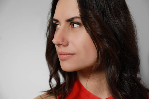 istock Young woman with nose piercing on grey background, closeup 1320297185