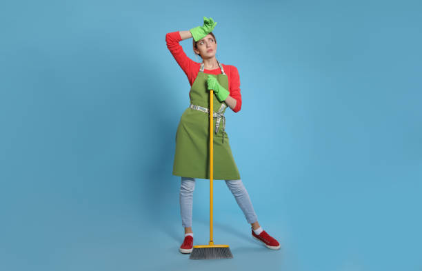 istock Young housewife with broom on light blue background 1320297243
