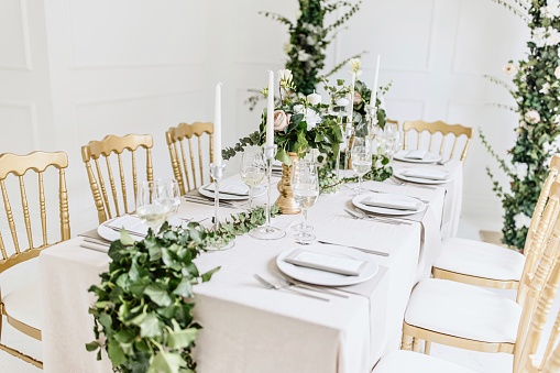 Beautiful wedding table in natural colors with bouquets of flowers and festive serving in garden.