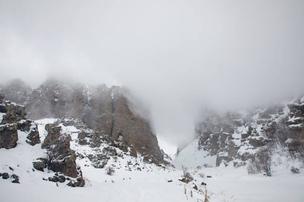 snowy landscape with high rocks in foggy day