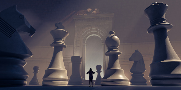 A small female figure in silhouette stands with hands on hips in contemplation, surrounded by huge chess pieces. The lone figure is framed by an ornate archway in a one wall of an imposing room with a very high ceiling.