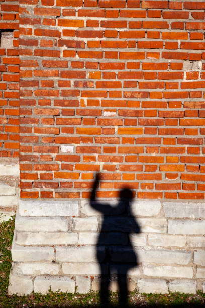 istock Shadow of a man on a brick wall 1320304250