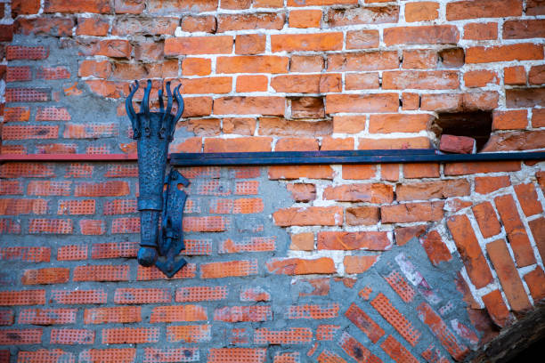 Section of an old dark brown brick wall with a small wooden wall.