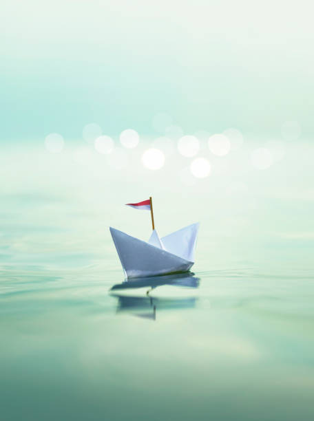 istock Paper Boat sailing on turquoise Water 1320306342