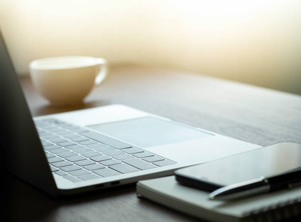 istock soft focus of Office desk table with keyboard of laptop computer, coffee cup and notebook, glasses. Business and finance concept. Workplace with morning sunlight from window with copy space. 1320316147