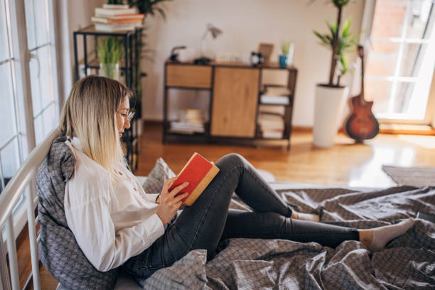 istock Woman reading a book in bed 1320316945