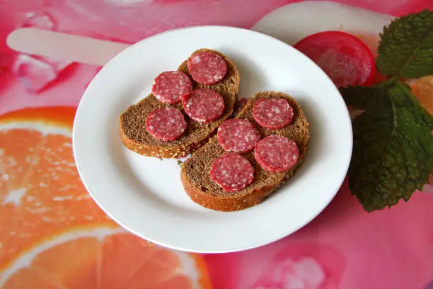 Photo of Two black bread sandwiches with salami