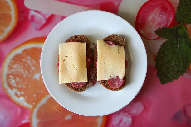 Photo of Two black bread sandwiches with salami and cheese, top view