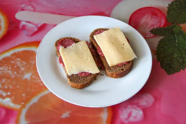 Photo of Two black bread sandwiches with salami and cheese