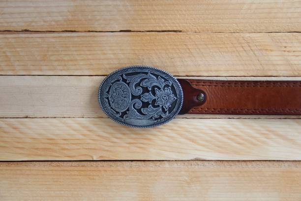 cinturón vaquero de cuero sobre fondo de madera - oval shape fotos fotografías e imágenes de stock