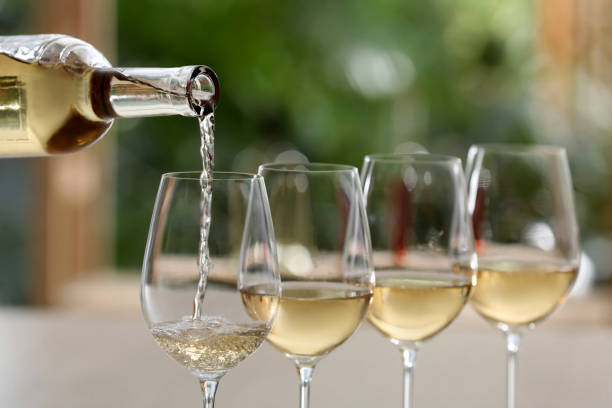 Pouring white wine from bottle stock photo