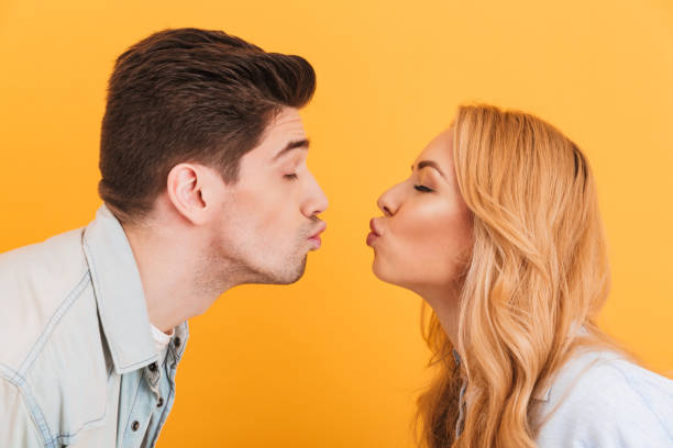 foto profilo di giovani bellissimi innamorati che esprimono amore e affetto mentre si baciano a occhi chiusi, isolati su sfondo giallo - baciare foto e immagini stock