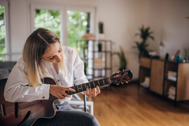 istock Woman playing guitar at home 1320324300