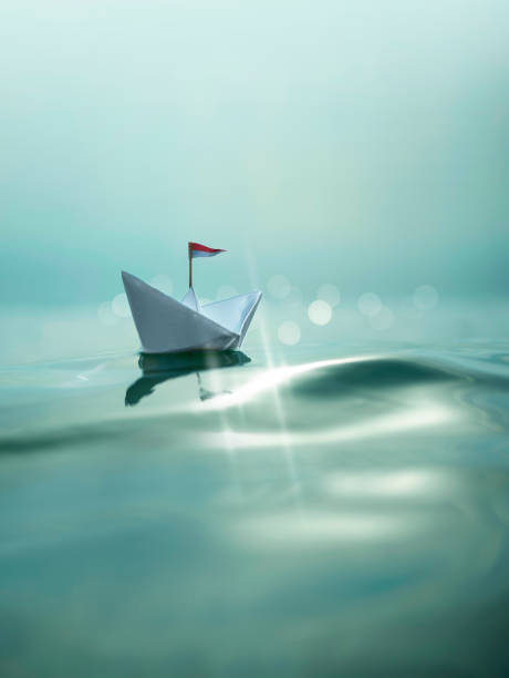istock Paper Boat sailing on turquoise Water 1320324348