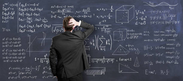 istock Education concept with back view on pensive man in black suit looking at chalkboard painted with mathematical formulas. 1320324586