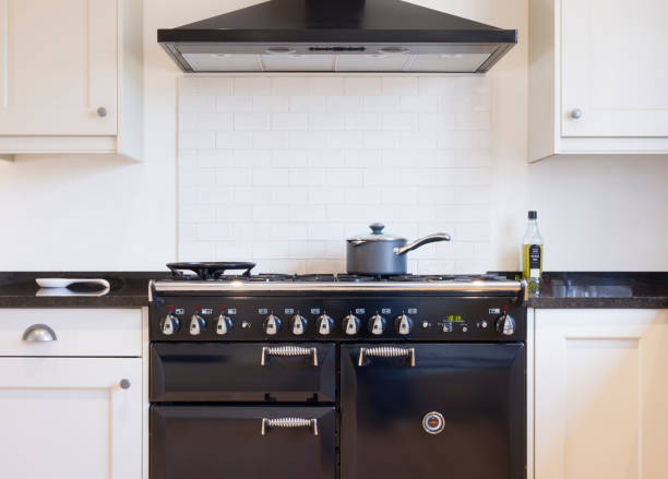 Black and white kitchen design UK Black and white kitchen design. Painted wood modern kitchen with black enamel range cooker and chimney hood. UK shaker style kitchen remodeling white units stock pictures, royalty-free photos & images