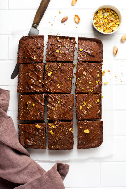 istock Chocolate squares with pistachio nuts and strawberries on white paper on a light background, top view, horizontal composition. Flat food 1320337776