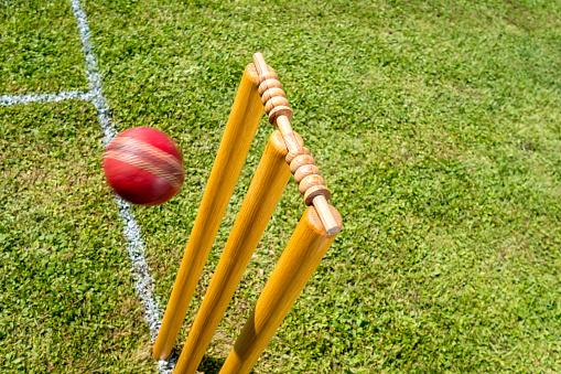 High angle view of cricket ball approaching stumps on the field.