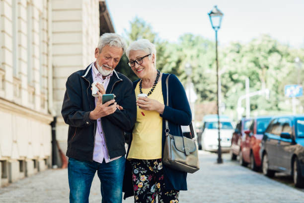 istock Happy senior couple walking, enjoying coffee and using smartphone 1320342021
