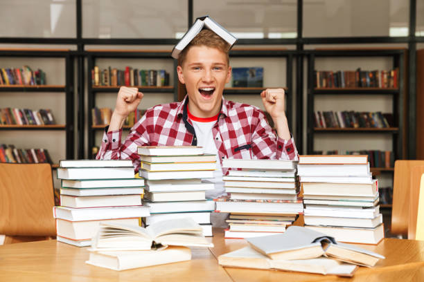 istock Happy teenage boy sitting at the library table 1320342514