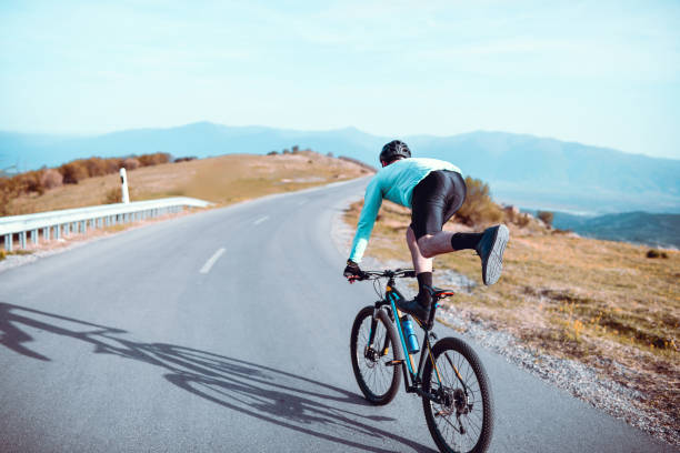 istock Male Performing Bicycle Tricks While Riding Downhill On Asphalt Road 1320346740