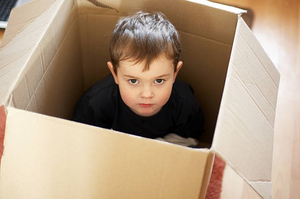 istock Young boy in a cardboard box looking sad 132034787